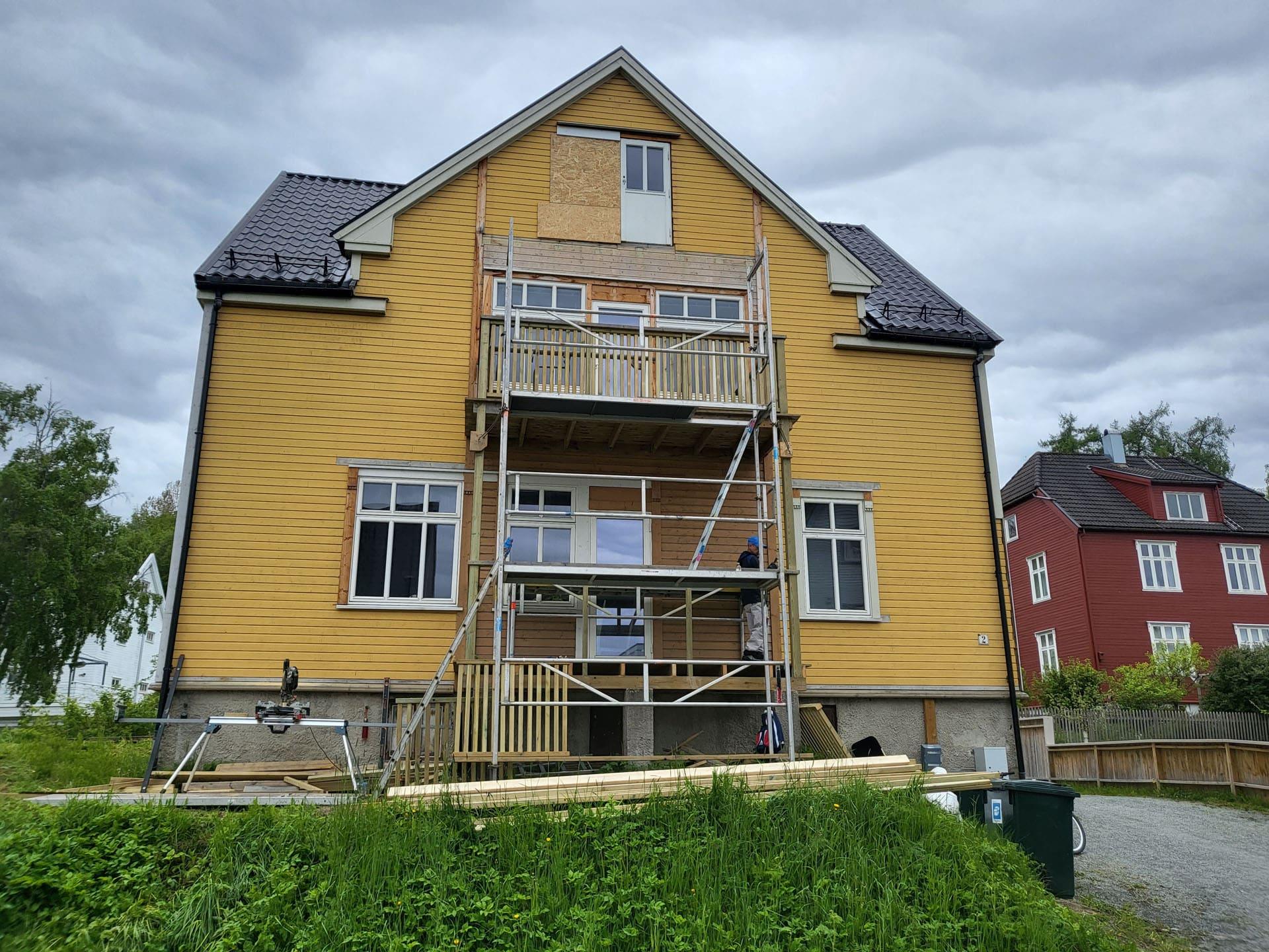 Gult trehus med rekonstruerte balkonger i flere etasjer