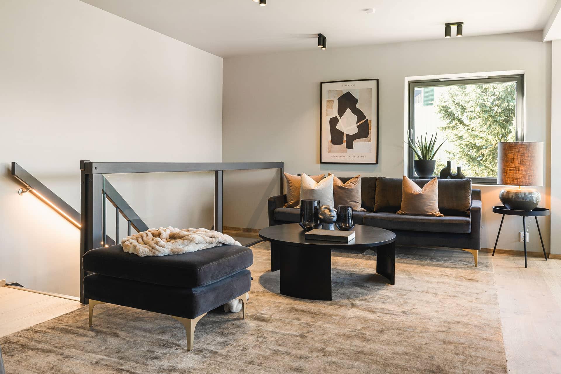Stue med lys sofa, rundt bord og store vinduer
